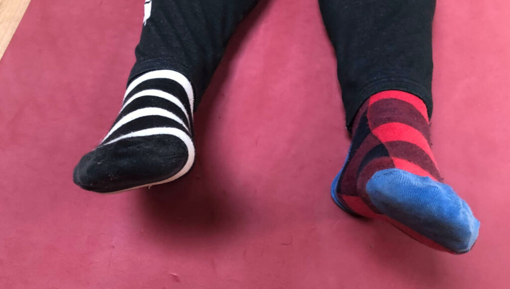 Two feed with two different socks. black and white striped, one with blue, red and black blocks